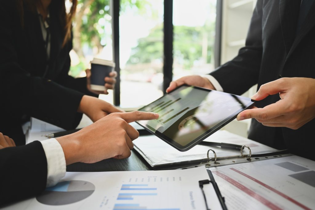 Economist team analyzing financial market on digital tablet screen at meeting table